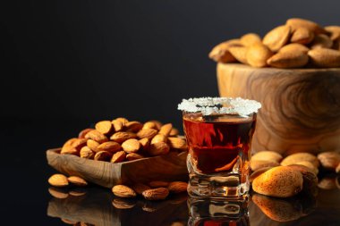 Güçlü alkolik İtalyan likörü Amaretto. Siyah arka planda badem fıstığı var..