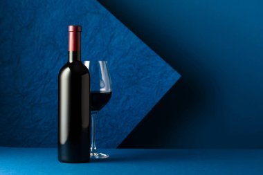 Mavi arka planda bir şişe kırmızı şarap. Metnin için boşluk kopyala.