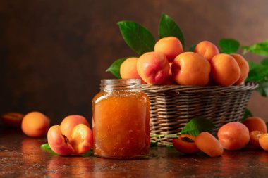 Cam kavanozda kayısı reçeli ve kahverengi bir masada taze meyve. Boşluğu kopyala.