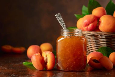 Cam kavanozda kayısı reçeli ve kahverengi bir masada taze meyve. Boşluğu kopyala.