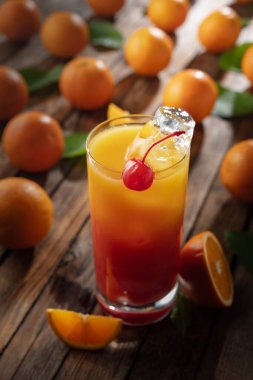 Klasik tekila gündoğumu kokteyli, portakal suyu ve nar şurubunun katmanlı renkleri, bir şişe maraska şişi ile süslenmiş..