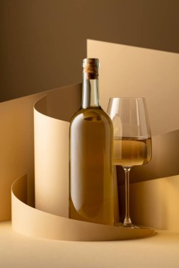 Bottle and glass of white wine on a beige background. Copy space.