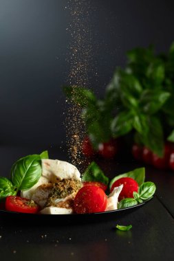 Fesleğenli Mozzarella, vişneli domates ve üzerine Akdeniz baharatları serpiştirilmiş pesto sosu. Geleneksel İtalyan mutfağı.