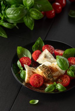 Fesleğenli Mozzarella, vişneli domates ve üzerine Akdeniz baharatları serpiştirilmiş pesto sosu. Geleneksel İtalyan mutfağı.