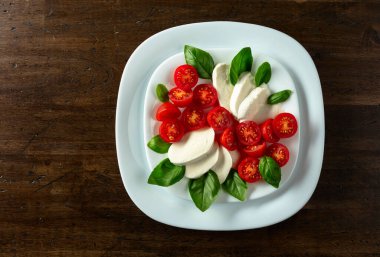 Ahşap bir masada fesleğen ve kiraz domatesli Mozzarella. Kopyalama alanı olan üst görünüm.
