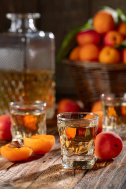 Apricot liqueur or grappa and fresh apricots on an old wooden table.