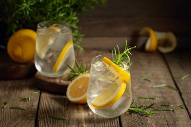 Eski ahşap bir masada buzlu, limonlu ve biberiyeli cin tonik. Boşluğu kopyala.