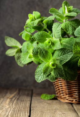 Eski ahşap bir masada, sepetteki taze nane. Boşluğu kopyala.