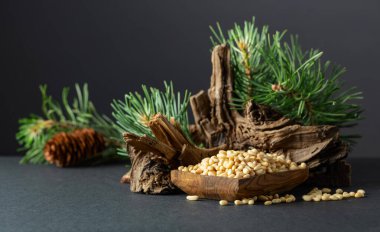 Çam fıstığı soyulmuş, sedir ağacı kurumuş ve yeşil dalları var. Siyah arka planda ahşap tabakta çam fıstığı.