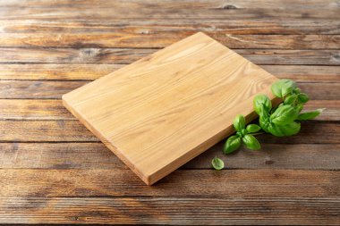 Tahta ve fesleğeni eski ahşap mutfak masasında kesiyorum. Mutfak geçmişi. Boş tahta kesme tahtası, ürün görüntüleme alanı.