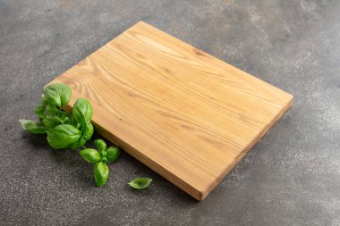 Mutfak masasında tahta ve fesleğen kesiyorum. Mutfak geçmişi. Boş tahta kesme tahtası, ürün görüntüleme alanı.