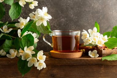 Bir fincan yasemin çayı ve ahşap masada taze yasemin çiçekleri..