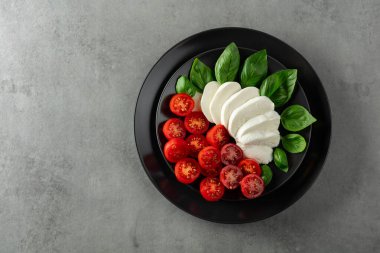 Siyah tabakta fesleğen ve kiraz domatesli Mozzarella. Kopyalama alanı olan üst görünüm.