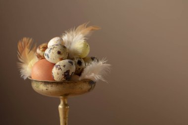 Bej arka planda pirinç kasede tüyleri olan Paskalya yumurtaları..