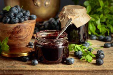 Eski ahşap bir masada taze böğürtlenli yabanmersini reçeli.