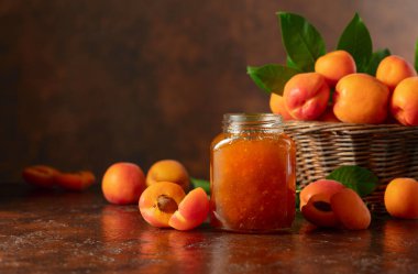 Cam kavanozda kayısı reçeli ve kahverengi bir masada taze meyve. Boşluğu kopyala.
