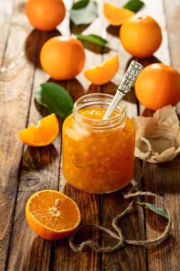Cam kavanozda portakal reçeli ve eski ahşap bir masada taze meyve..