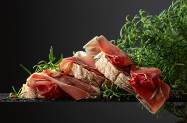 Siyah arka planda prosciutto ve biberiyeli Ciabatta. Geleneksel İtalyan atıştırması.