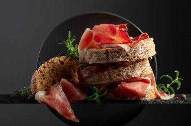 Siyah arka planda prosciutto ve biberiyeli Ciabatta. Geleneksel İtalyan atıştırması.