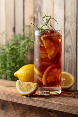 Buzlu çay ya da eski ahşap bir masada buzlu, biberiyeli ve limon dilimli alkollü kokteyl. Taze, sağlıklı, soğuk limon suyu. Buzlu ve limonlu çay..