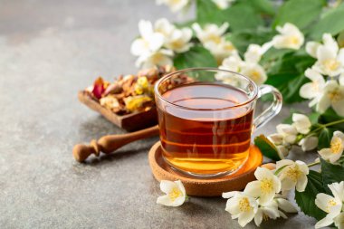 Bir fincan yasemin çayı ve taş bir masada taze yasemin çiçekleri. Boşluğu kopyala.