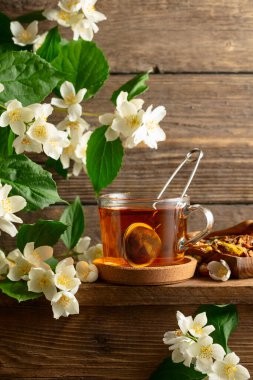 Bir fincan yasemin çayı ve ahşap masada taze yasemin çiçekleri..