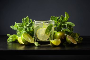 Siyah ahşap bir masada buzlu, limonlu ve naneli mojito..