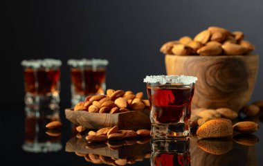 Güçlü alkolik İtalyan likörü Amaretto. Siyah arka planda badem fıstığı var..