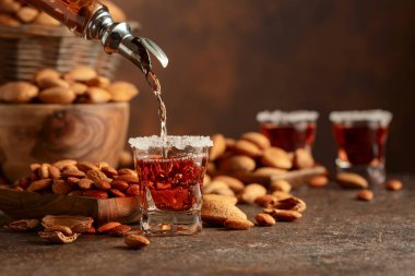 Alkolik İtalyan likörü Amaretto. Şarap masasında badem fıstığı var. Boşluğu kopyala.
