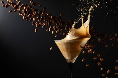 Espresso Martini, su sıçraması ve siyah arka planda kahve çekirdekleri. Boşluğu kopyala.