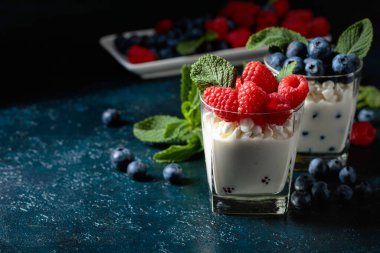 Kremalı süzme peynir, ahududu ve mavi bir masada yabanmersini..