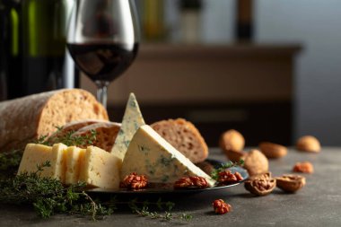 Mutfak masasında peynir, ekmek, kırmızı şarap ve ceviz. Geleneksel Akdeniz atıştırmalıkları.