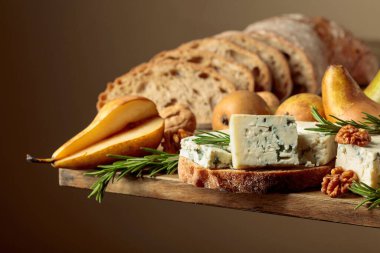 Mavi peynirli ve armutlu sandviç. Eski ahşap bir masa ekmeği, mavi peynir, armut, ceviz ve biberiye.