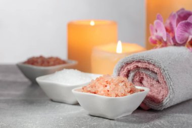 Deniz tuzu, havlular, orkide çiçekleri ve gri arka planda yanan mumlar. Kopyalama alanı ile kaplıca kavramı.