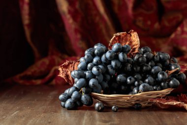 Eski ahşap bir masada bir demet mavi üzüm.