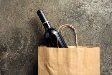 Eski bir taştan arka planda kırmızı şarap şişesi olan kağıt alışveriş torbası. Üst görünüm, alanı kopyala.