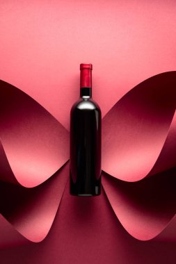 Kırmızı arka planda bir şişe kırmızı şarap. Üst görünüm.