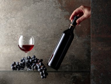 Bir şişe kırmızı şaraba uzanır. Pahalı şarapların konsepti. Metnin için boş yer.