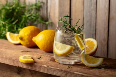 Eski ahşap bir masada buzlu, biberiyeli ve limonlu yaz ferahlatıcı bir içecek. Taze, sağlıklı, soğuk limon suyu. Buzlu ve limonlu su.