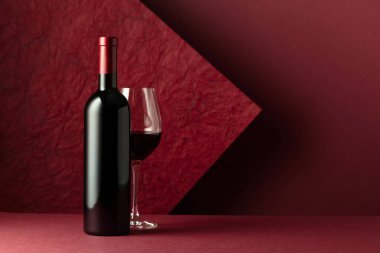 Kırmızı arka planda bir şişe kırmızı şarap. Metnin için boşluk kopyala.