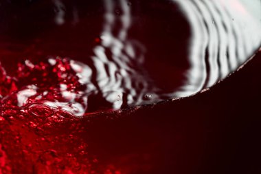 Kırmızı şarap bardakta soyut olarak sıçrıyor. Makro atış. Boşluğu kopyala.