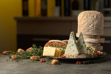 Mutfak masasında peynir, ekmek, ceviz ve kekik. Arka planda çeşitli şarap şişeleri var. Geleneksel Akdeniz atıştırmalıkları.