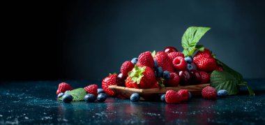Stüdyoda çilek, yabanmersini, ahududu ve tatlı vişne karışımı koyu mavi arka planda..