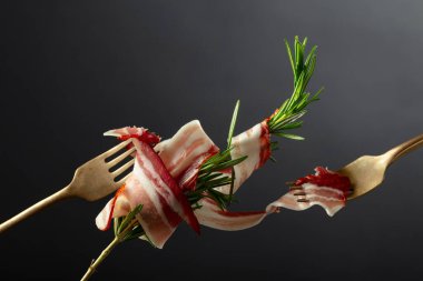 Siyah arka planda biberiyeli kurutulmuş domuz pastırması. Çatalda dilimlenmiş pastırma..