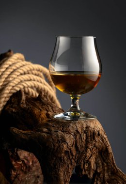 Konyak bardağı ve ip eski bir ahşap çıkmazda. Viski, konyak ya da koyu bir arka planda konyak..