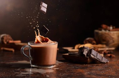 Koyu çikolata parçaları bir bardak kakao içeceğinin içine düşer ve güzel bir su sıçratır. Boşluğu kopyala.