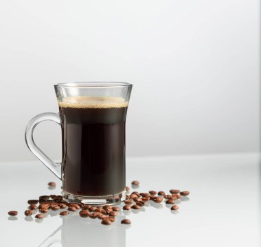 Cam sehpanın üzerinde bir fincan kahve ve kahve çekirdeği. Boşluğu kopyala.