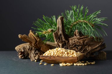 Çam fıstığı soyulmuş, sedir ağacı kurumuş ve yeşil dalları var. Siyah arka planda ahşap tabakta çam fıstığı.