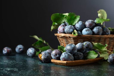 Mutfak masasında yaprakları olan olgun mavi erikler..