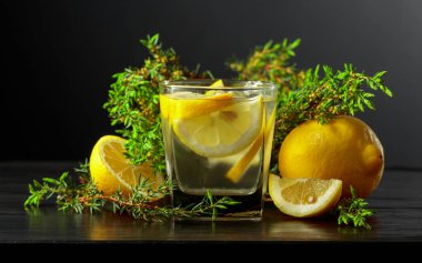Siyah ahşap bir masada buz, limon ve ardıç dallı kokteyl cin toniği..